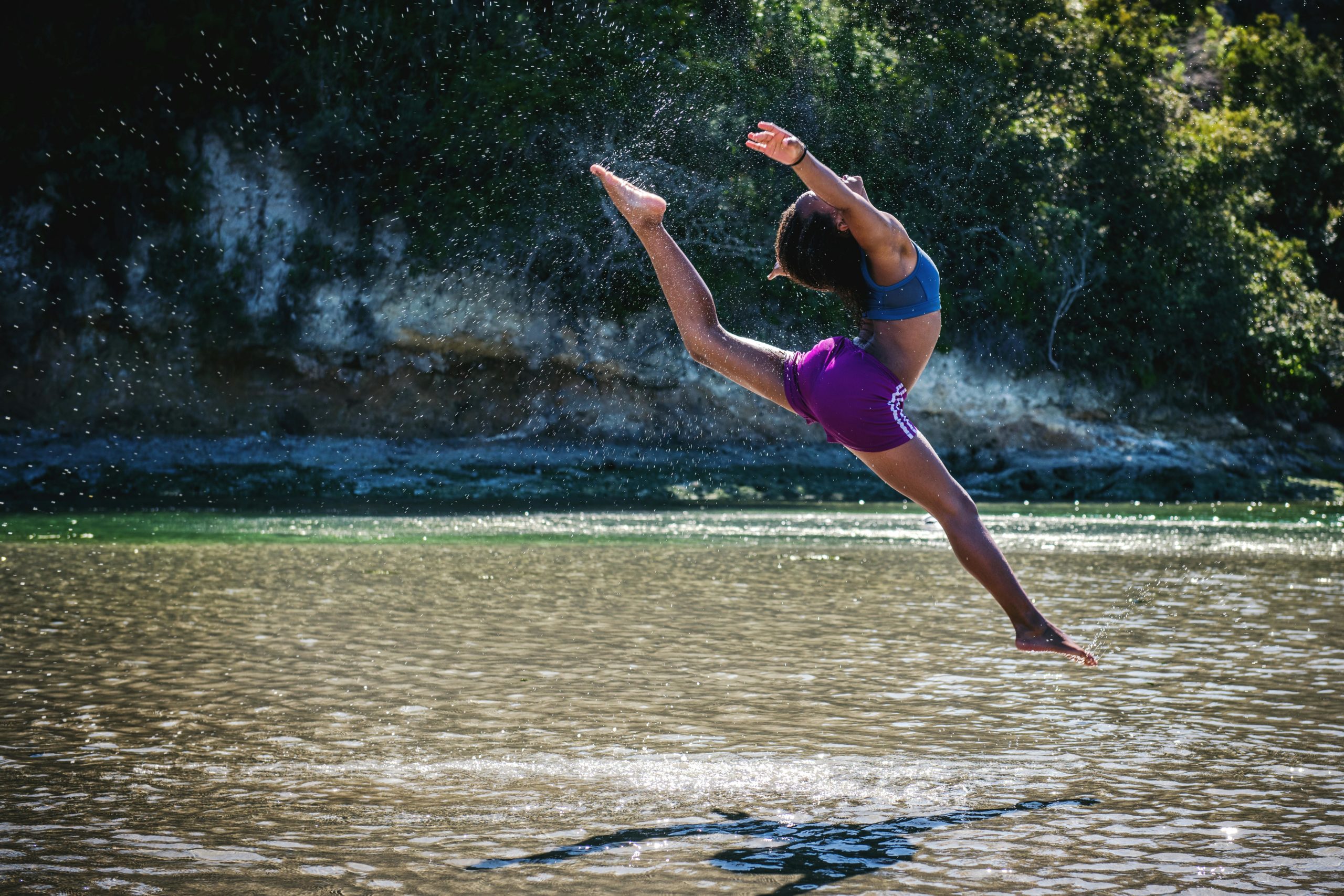 Une femme, qui saute au dessus d'une rivière